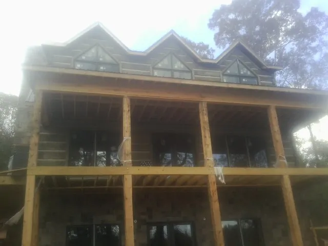 Dormers and porch framing on a large log home under construction — Roof Coating work by our crew in Climax